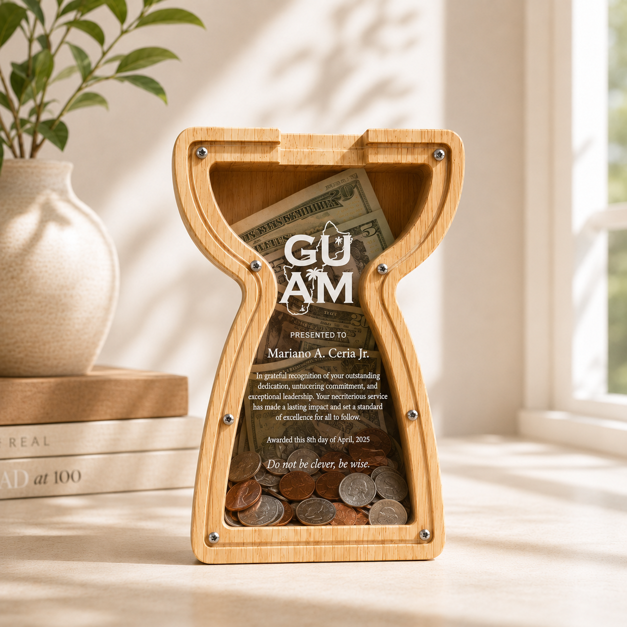 The personalized 7.5-inch latte stone wooden savings piggy bank shown standing on a studio table, filled with collected coins behind the clear acrylic cover featuring custom 'GUAM' branding.