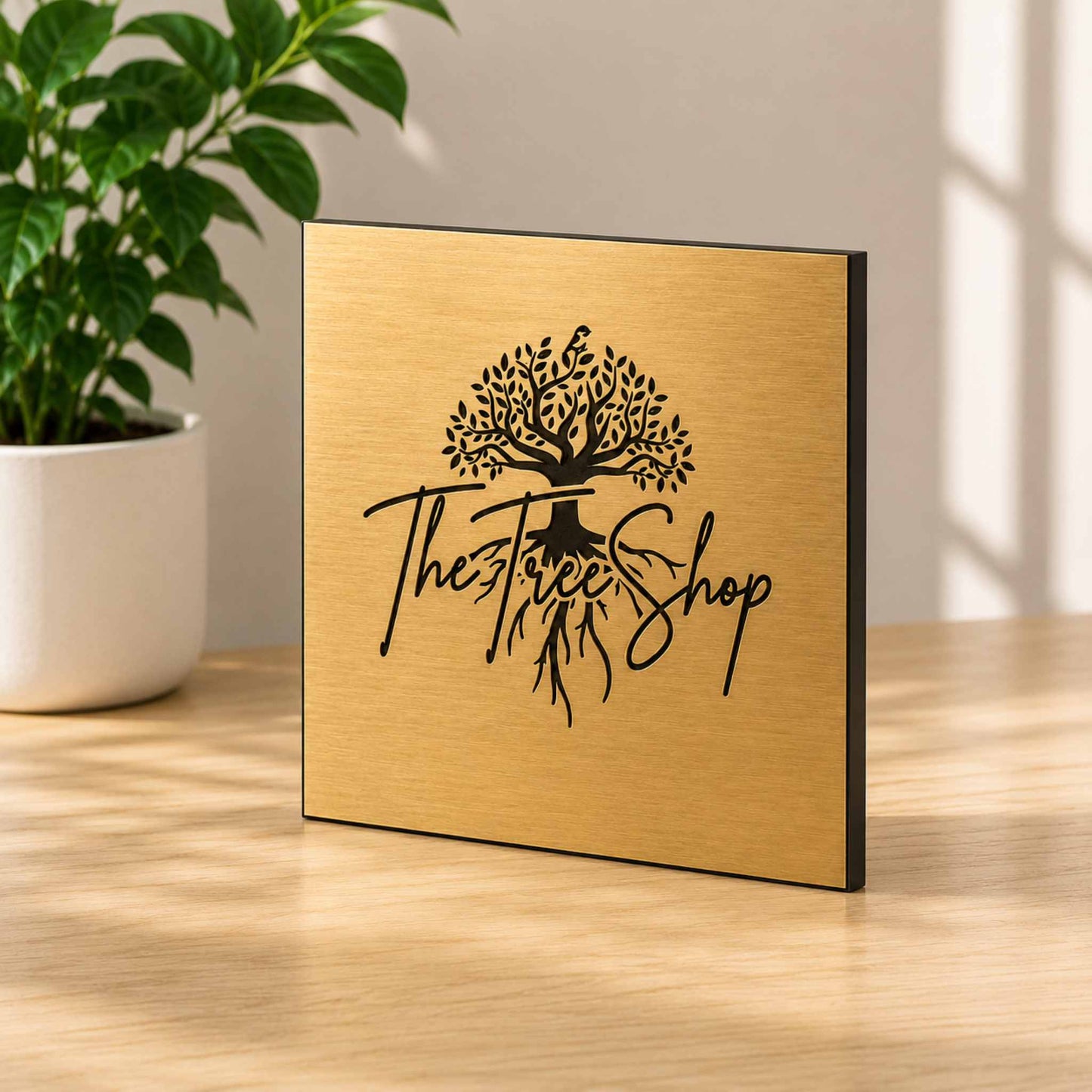 Brushed brass metal plaque with engraved business logo displayed in modern daylight interior