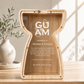 A large 12-inch custom laser-engraved wooden piggy bank and shadow box award carved into a Guam latte stone silhouette with a clear acrylic front window panel, displayed on a sunlit wooden office desk next to a white ceramic vase.