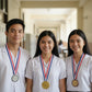 Three smiling school students standing together in a bright hallway wearing their personalized custom graduation or academic honor medals with patriotic red, white, and blue neck necklines.