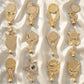 A collection of twelve different personalized brilliant gold trophy toppers featuring stars, victory wreaths, and classic academic motifs arranged on a soft white satin fabric background.