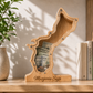 The personalized Guam Island wooden shadow box savings bank displayed on a wooden shelf, filled with folded dollar bills visible behind the clear acrylic front panel.