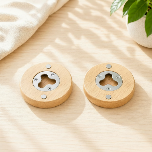 Two personalized round wooden bottle openers placed side by side on a light wood studio table under gentle shadows, showcasing the metal opening mechanism and the heavy-duty black magnetic backing.