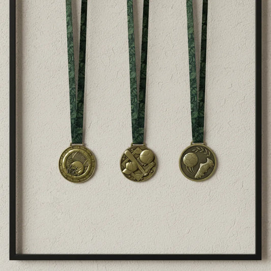 A minimalist shadow box wall display showcasing three personalized antique bronze sports medals hanging neatly by their green neck ribbons against a soft beige textured backdrop.