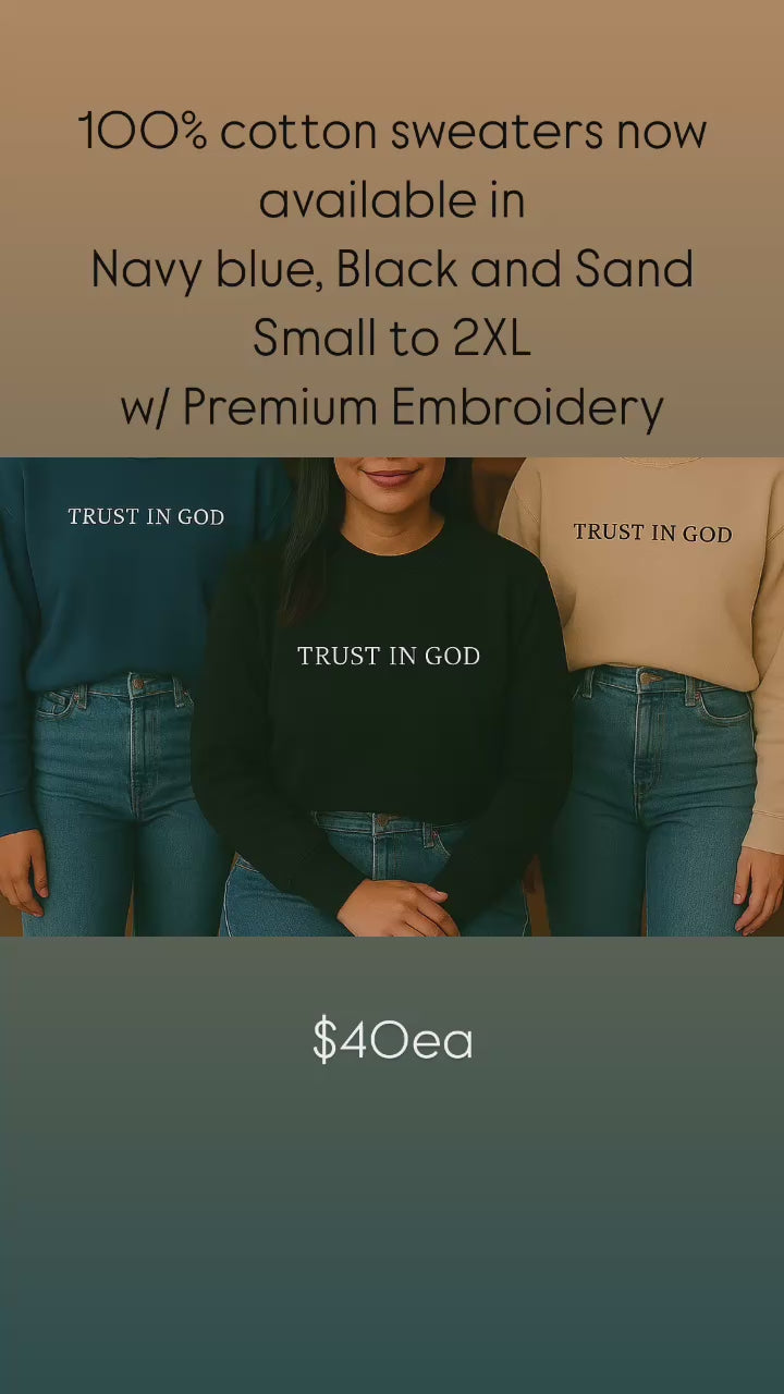 Video thumbnail highlighting premium 100% cotton crewneck sweaters with white custom text embroidery reading 'TRUST IN GOD', available in navy, black, and sand color options.